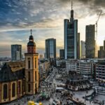 A stunning cityscape of Frankfurt featuring skyscrapers and a historic church at sunset.