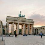 Scenic view of Berlin's Brandenburg Gate with people gathering at sunset.