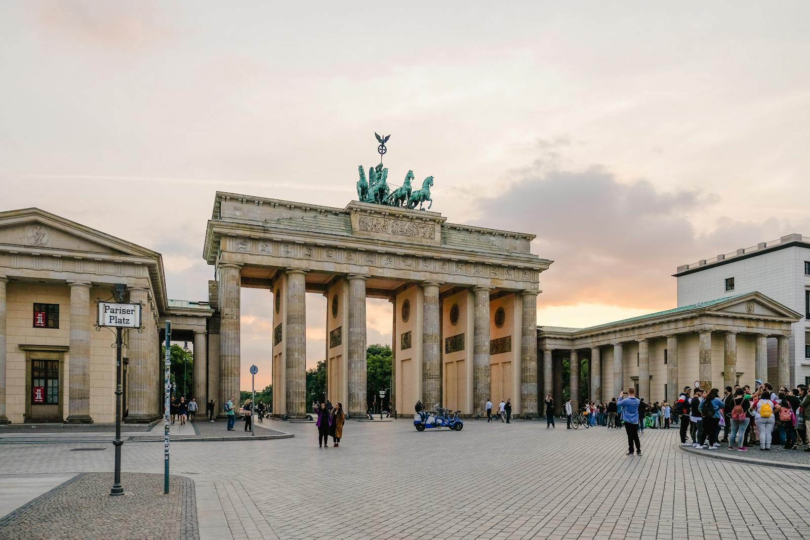 Scenic view of Berlin's Brandenburg Gate with people gathering at sunset.