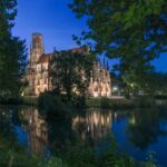 St John's Church illuminated at night, reflecting on a tranquil Stuttgart lake.