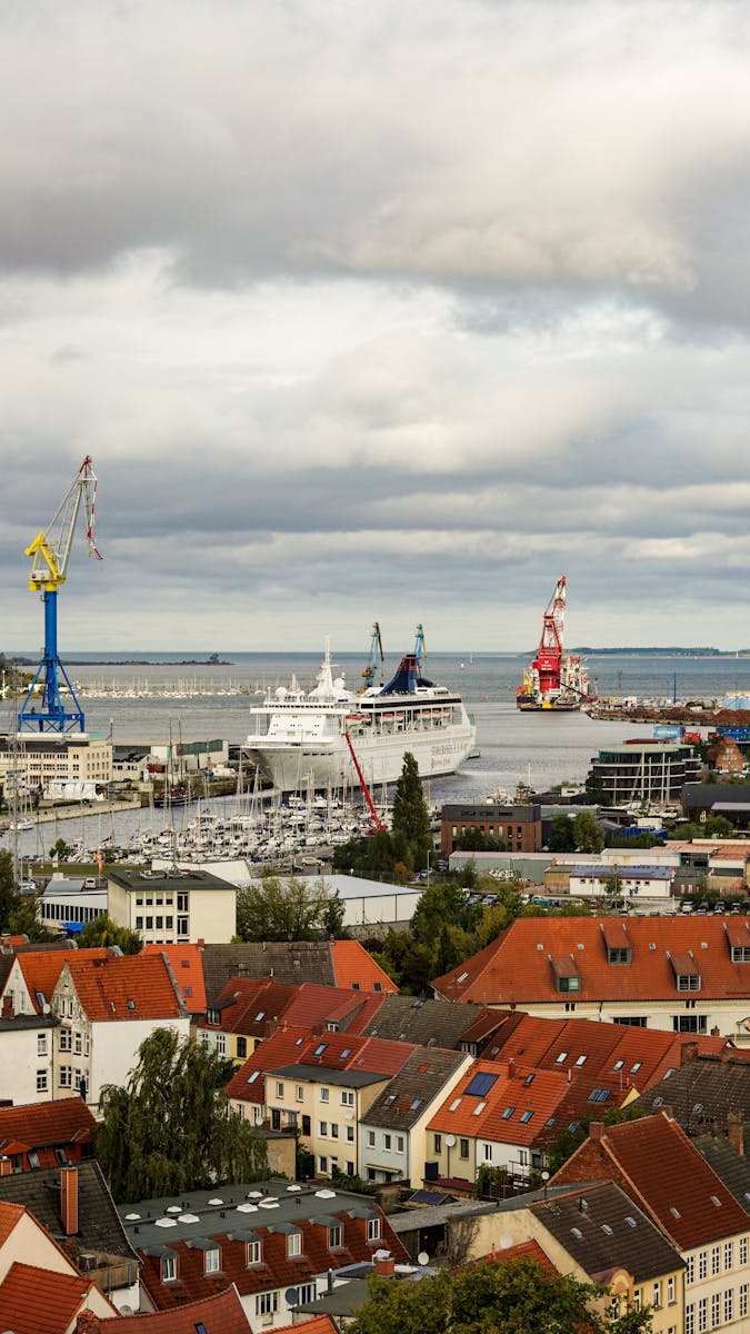 Aerial view of a bustling harbor with ferries and vibrant red-tiled rooftops under a cloudy sky.