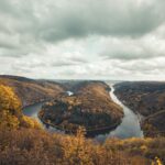 A breathtaking aerial view of the Saar River bend surrounded by lush autumn foliage in Mettlach, Germany.