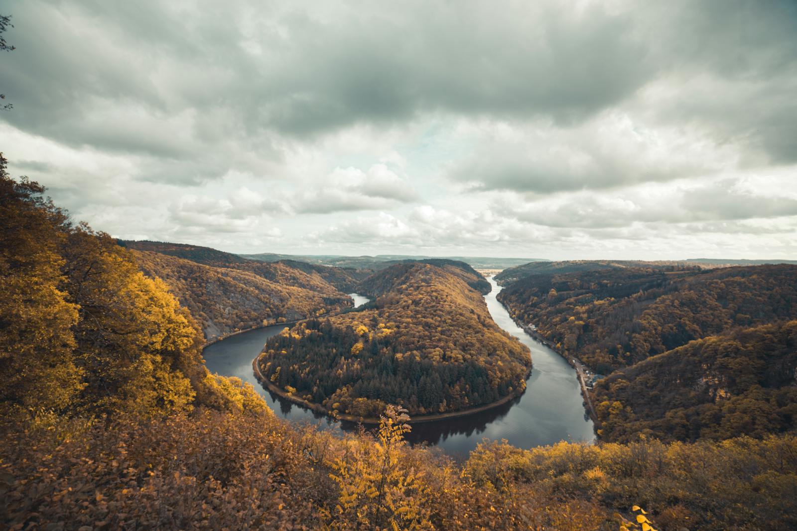 A breathtaking aerial view of the Saar River bend surrounded by lush autumn foliage in Mettlach, Germany.