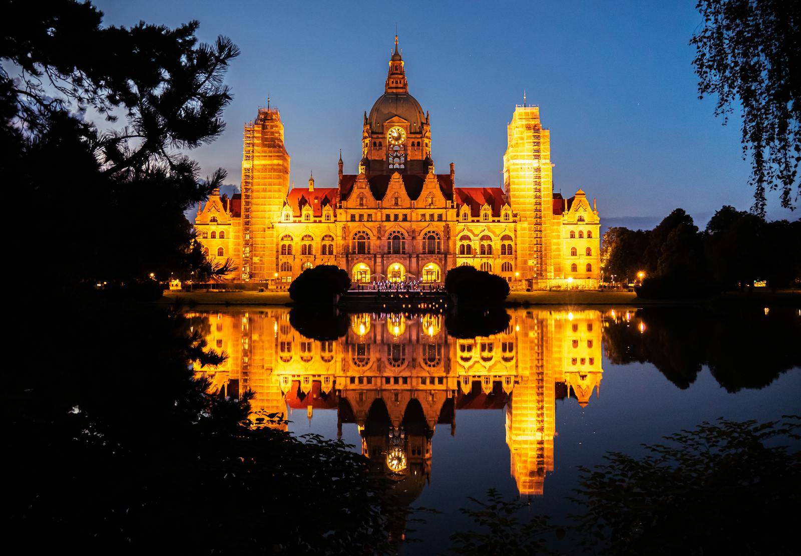 Stunning view of Hannover's New Town Hall illuminated at night, reflecting on tranquil water.