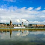 white ferris wheel near body of water under blue sky during daytime